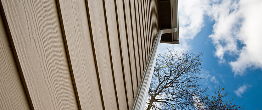 wood side panels on house with gutter and blue sky